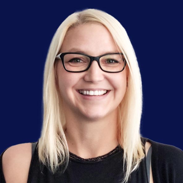 Anna Karoń's - the author of the blog post - headshot picture on a blank background. She's is a blonde with medium length hair wearing black glasses, and black clothes. She is smiling