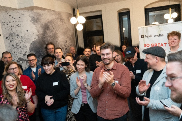 People gathered indoors applauding during a Hyva and Mollie community,partner event