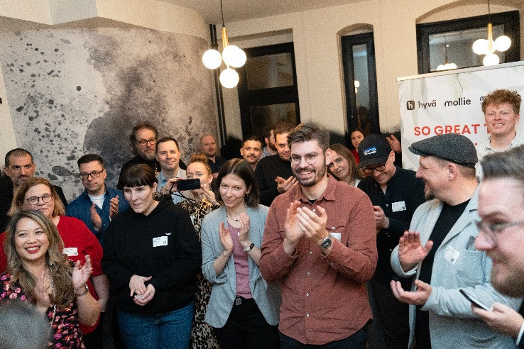 People gathered indoors applauding during a Hyva and Mollie community,partner event